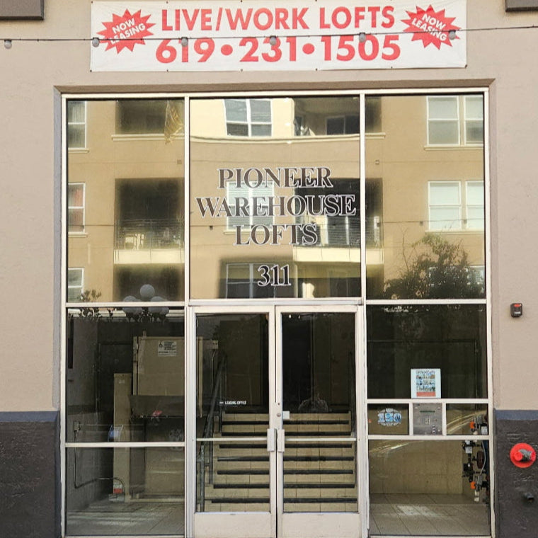 Commercial PIONEER WAREHOUSE building entrance with a sign for 'Live/Work Lofts' and contact information.
