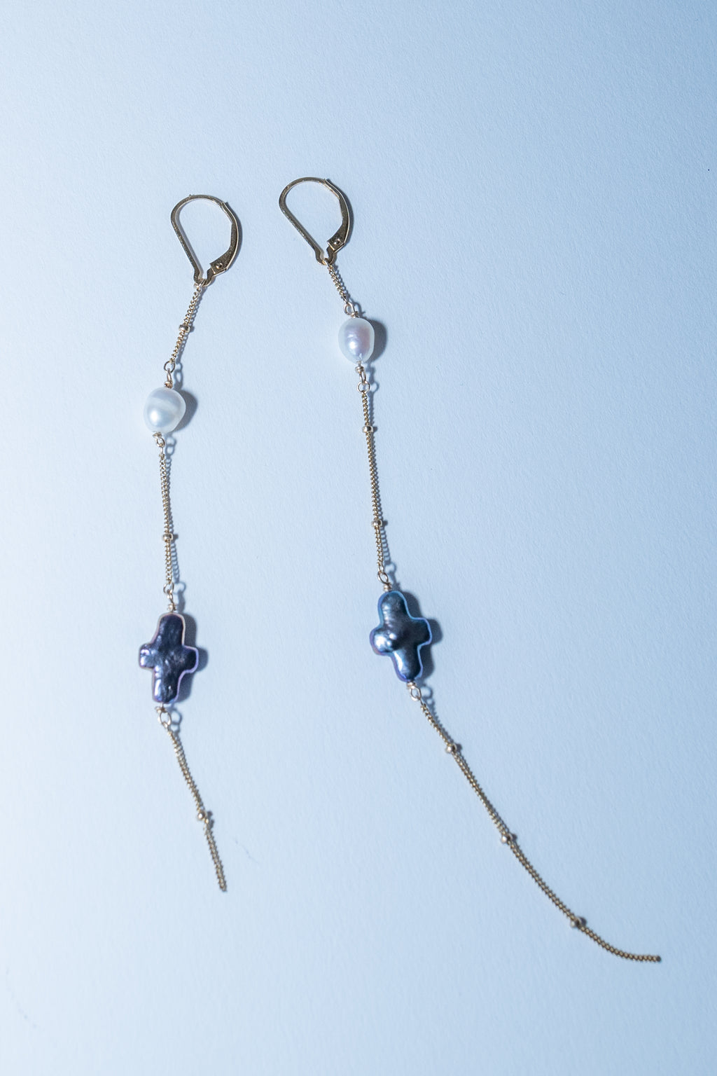 Pair of beaded earrings with cross designs on a light blue background