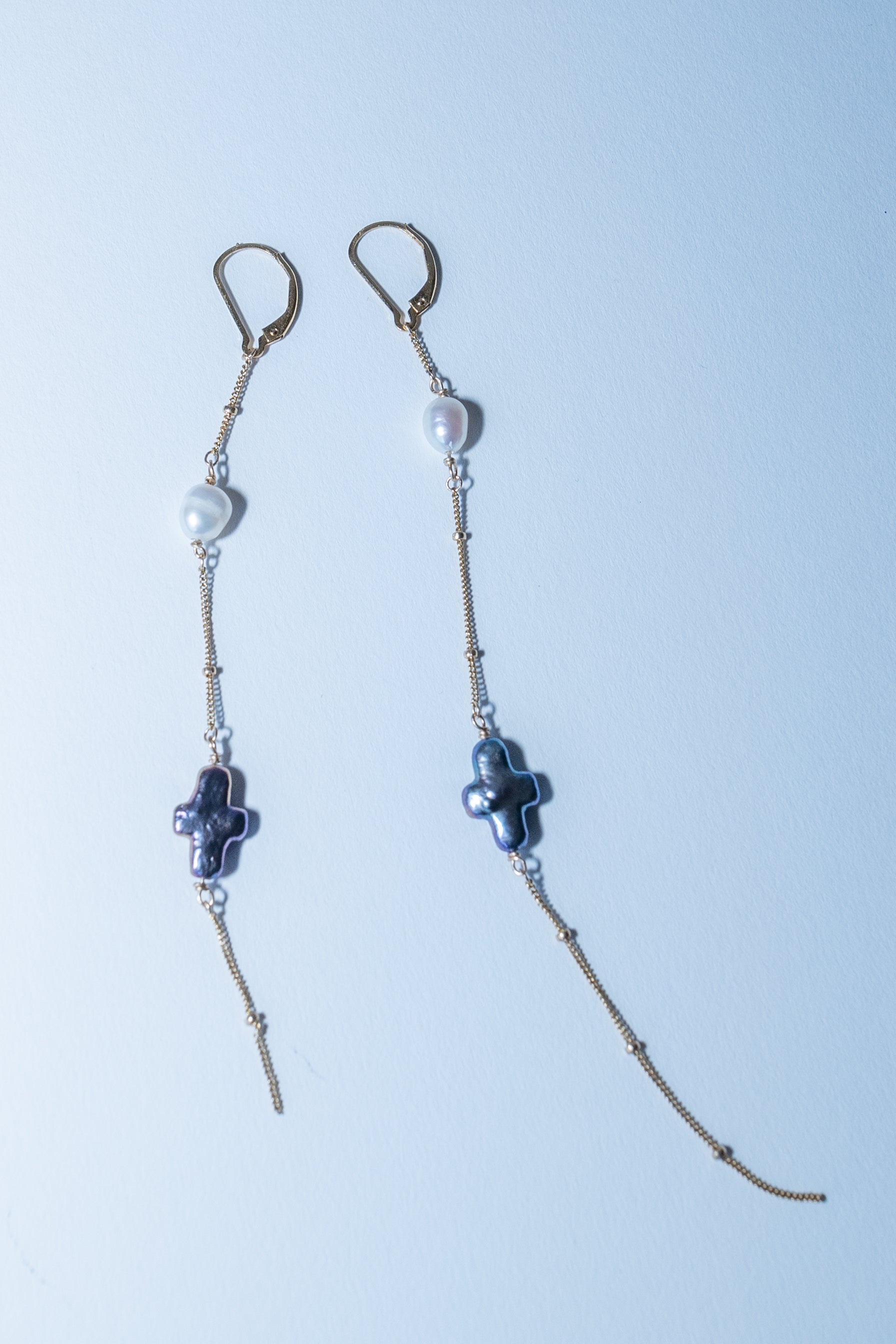 Pair of beaded earrings with cross designs on a light blue background
