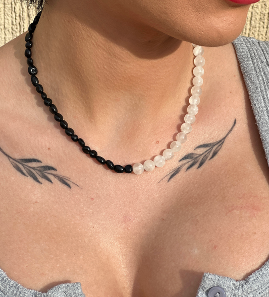 A close-up image of a woman wearing a black and white CRYSTAL necklace with a geometric design on her neck.