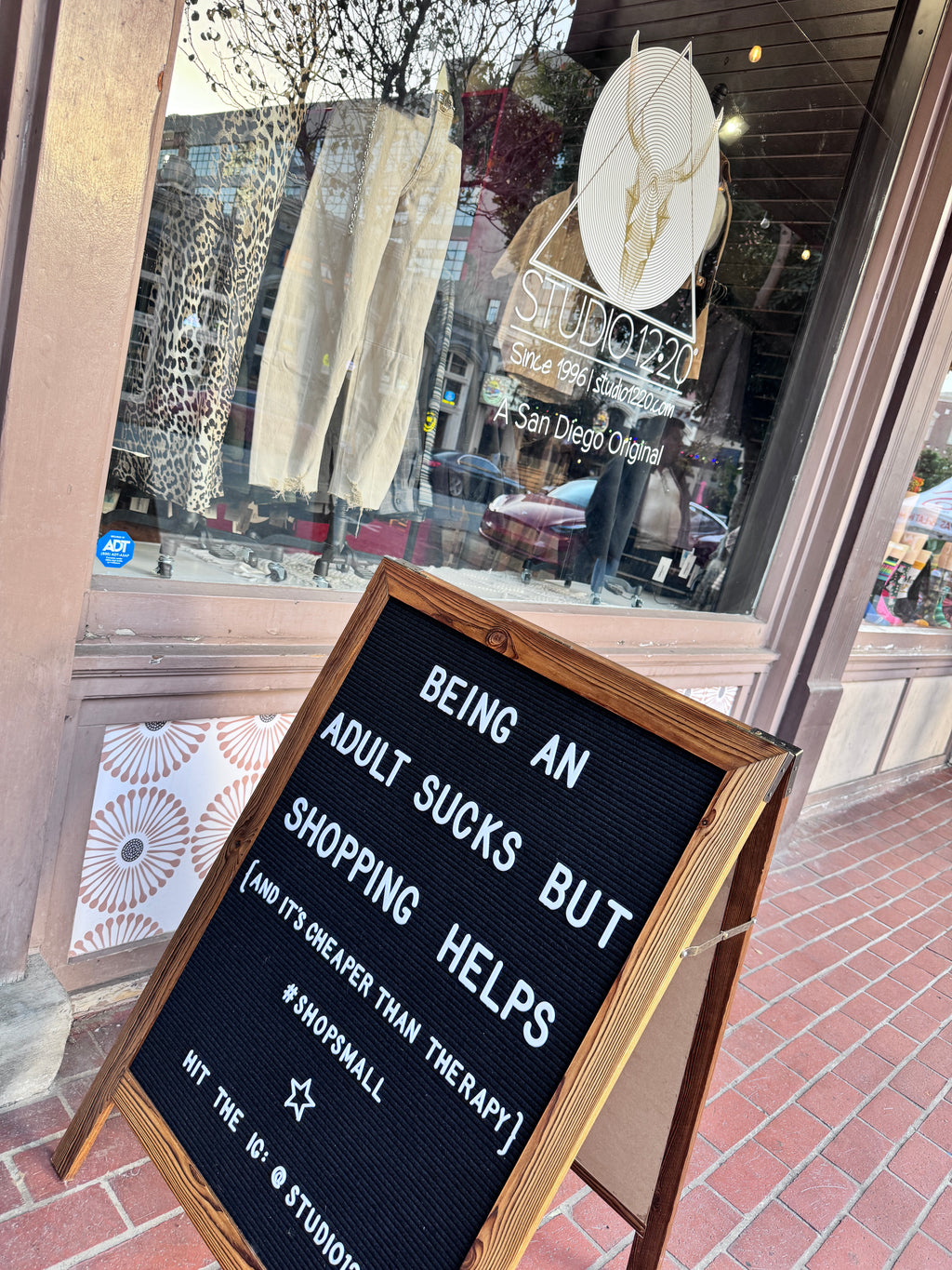 Storefront window with a sign about shopping and therapy, reflected glass