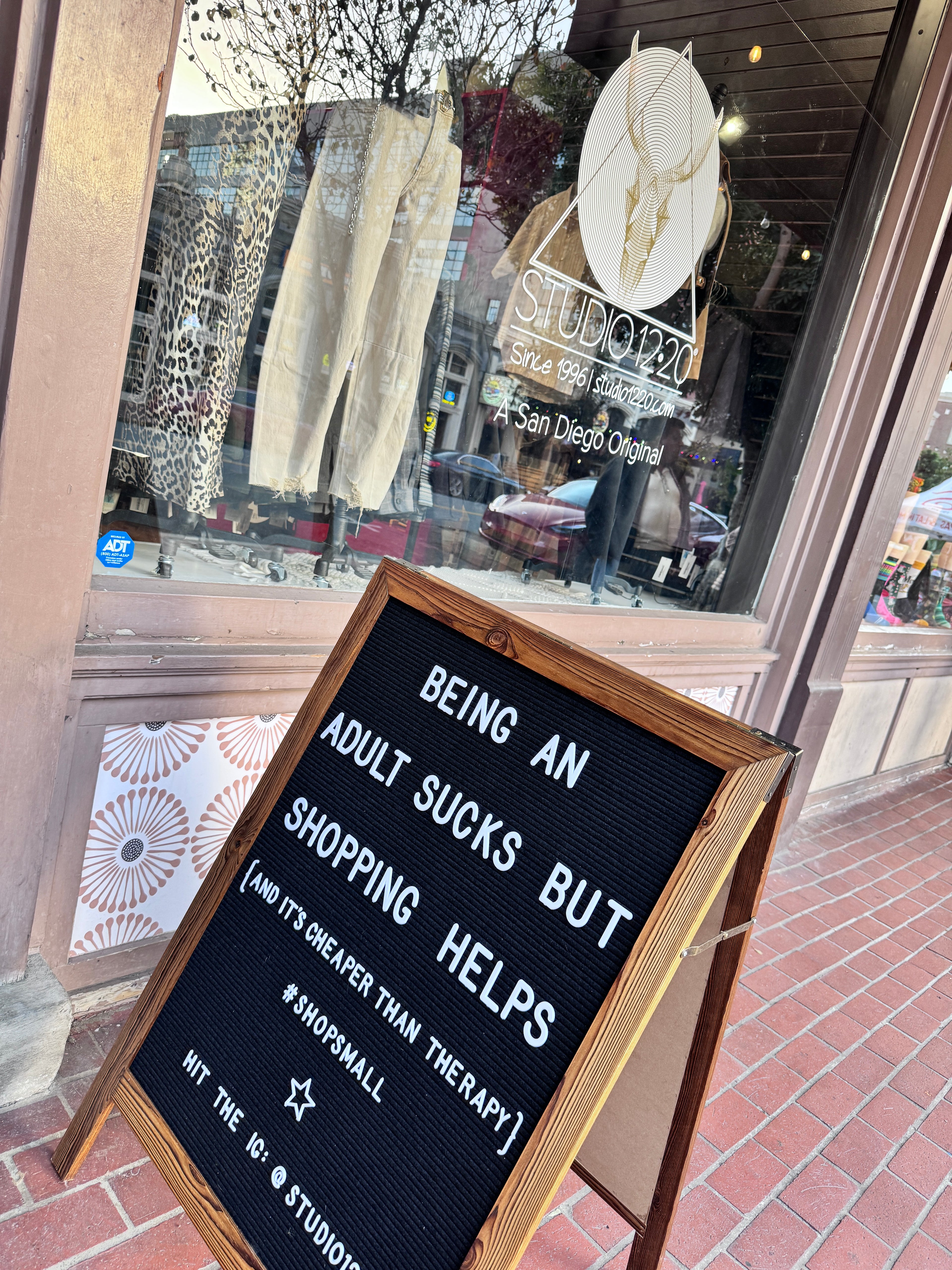 Storefront window with a sign about shopping and therapy, reflected glass