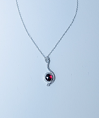 Silver necklace with a red gemstone pendant on a light gray background