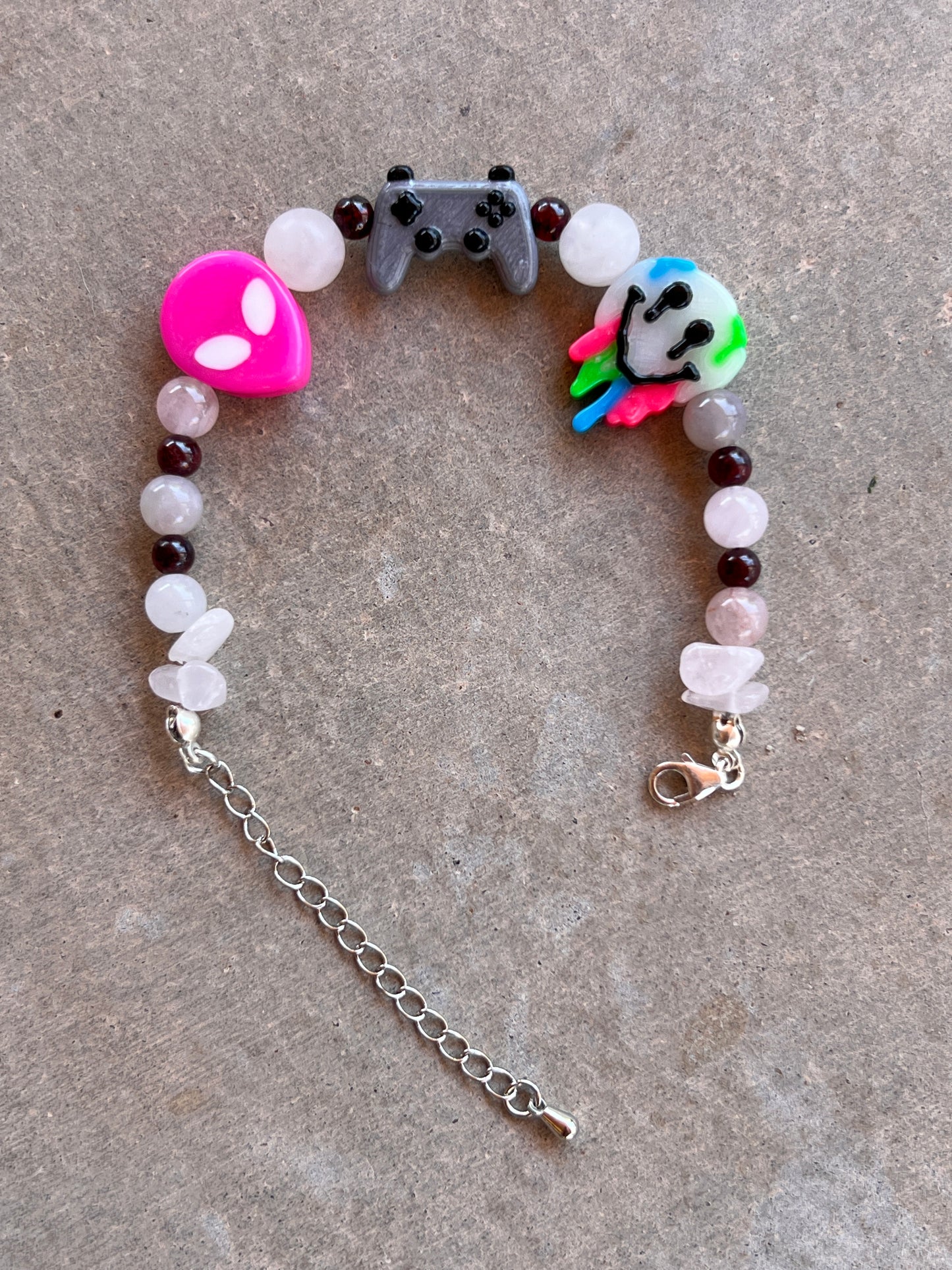 A multicolored beaded bracelet with a gaming controller and animal head charms, finished with a silver clasp.