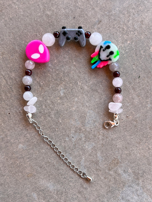A multicolored beaded bracelet with a gaming controller and animal head charms, finished with a silver clasp.