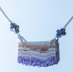 Necklace with a purple and beige stone pendant on a white background