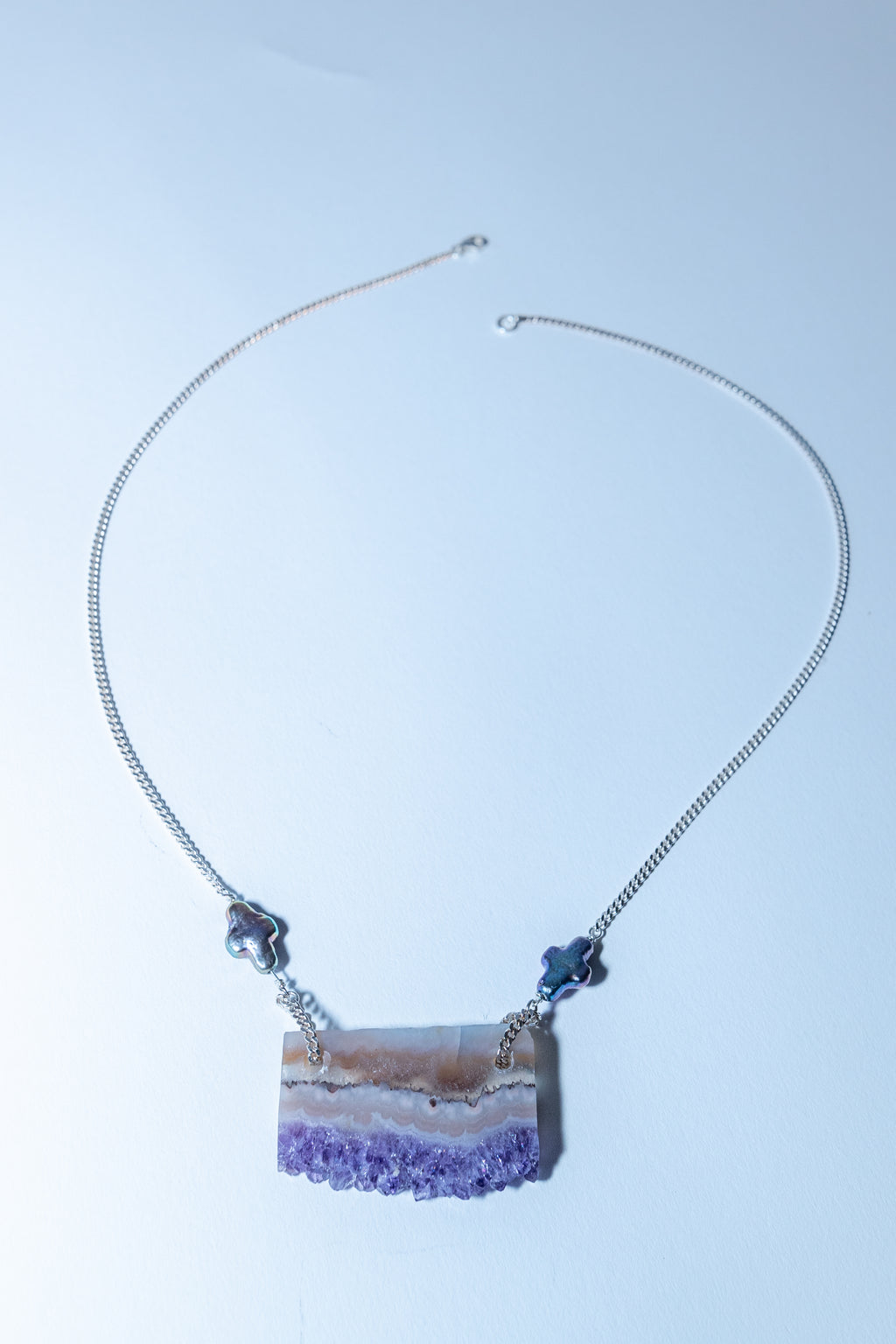 Necklace with a purple crystal pendant on a light blue background