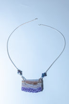 Necklace with a purple crystal pendant on a light blue background