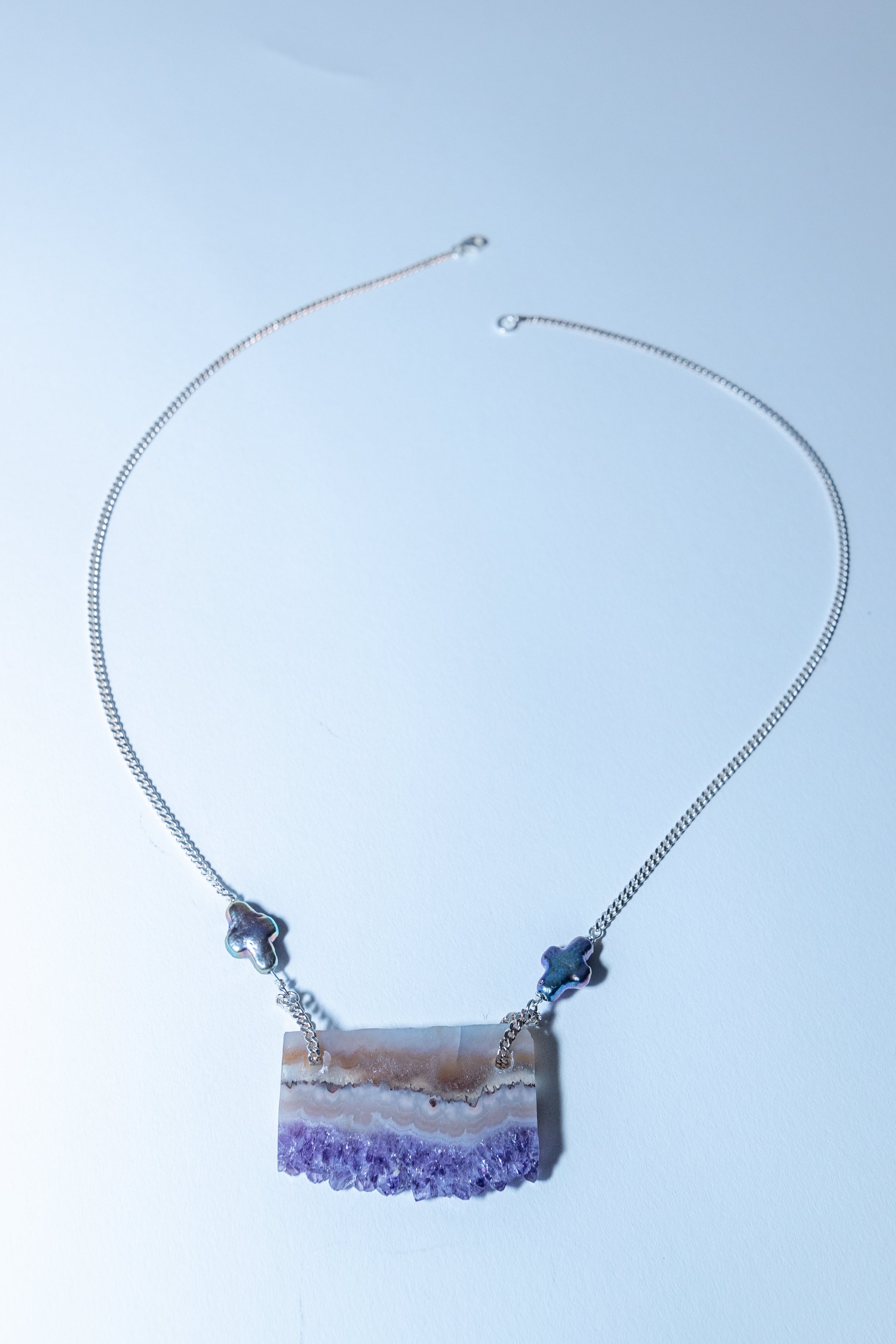 Necklace with a purple crystal pendant on a light blue background