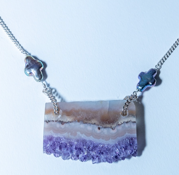 Necklace with a purple and beige stone pendant on a white background