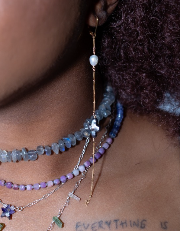 Close-up of a person wearing multiple beaded necklaces with a blurred background