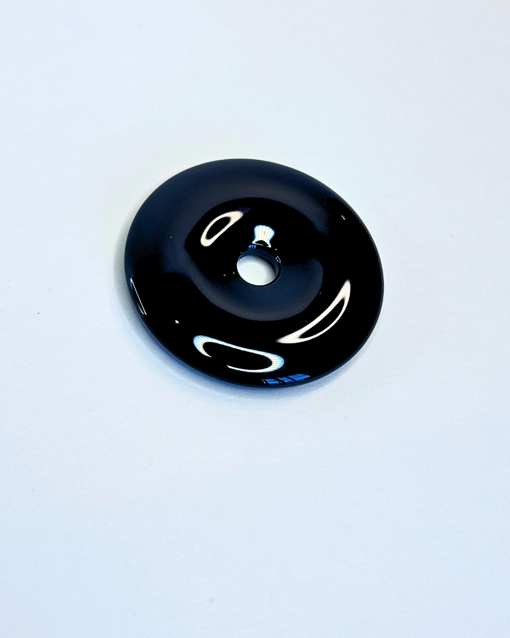 Black circular object on a light gray background