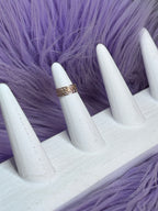 Gold ring on a white mannequin hand against a purple fur background