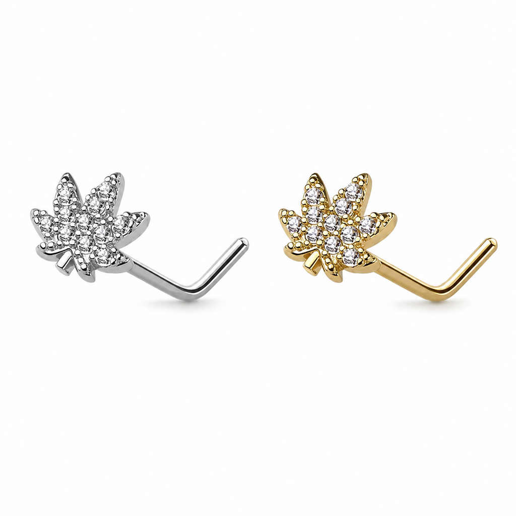 Two small leaf-shaped stud piercings for nose on a plain white background, one in silver and one in yellow gold, both set with clear stones.