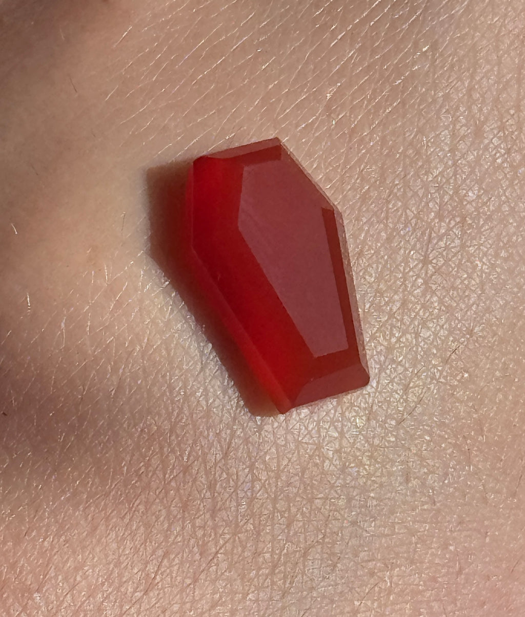 Red coffin-shaped object on a beige surface