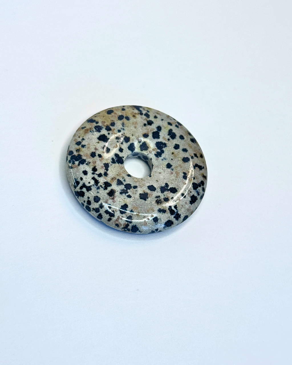 Decorative stone disc with black speckles on a white background