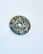 Decorative stone disc with black speckles on a white background