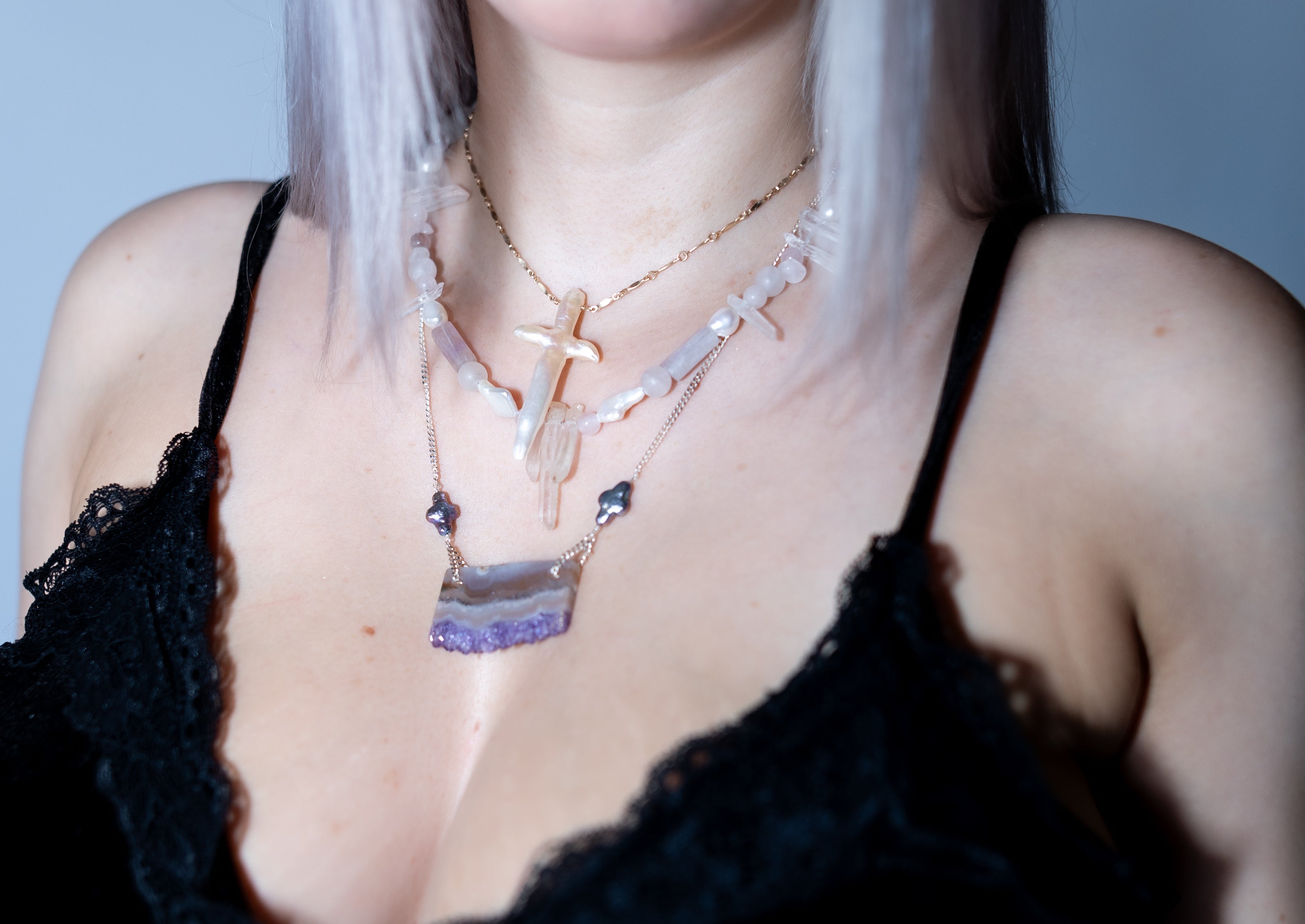 Person wearing multiple necklaces with a blurred background