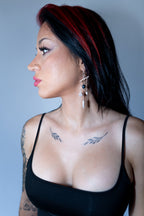 Woman with tattoos wearing a black top against a gray background