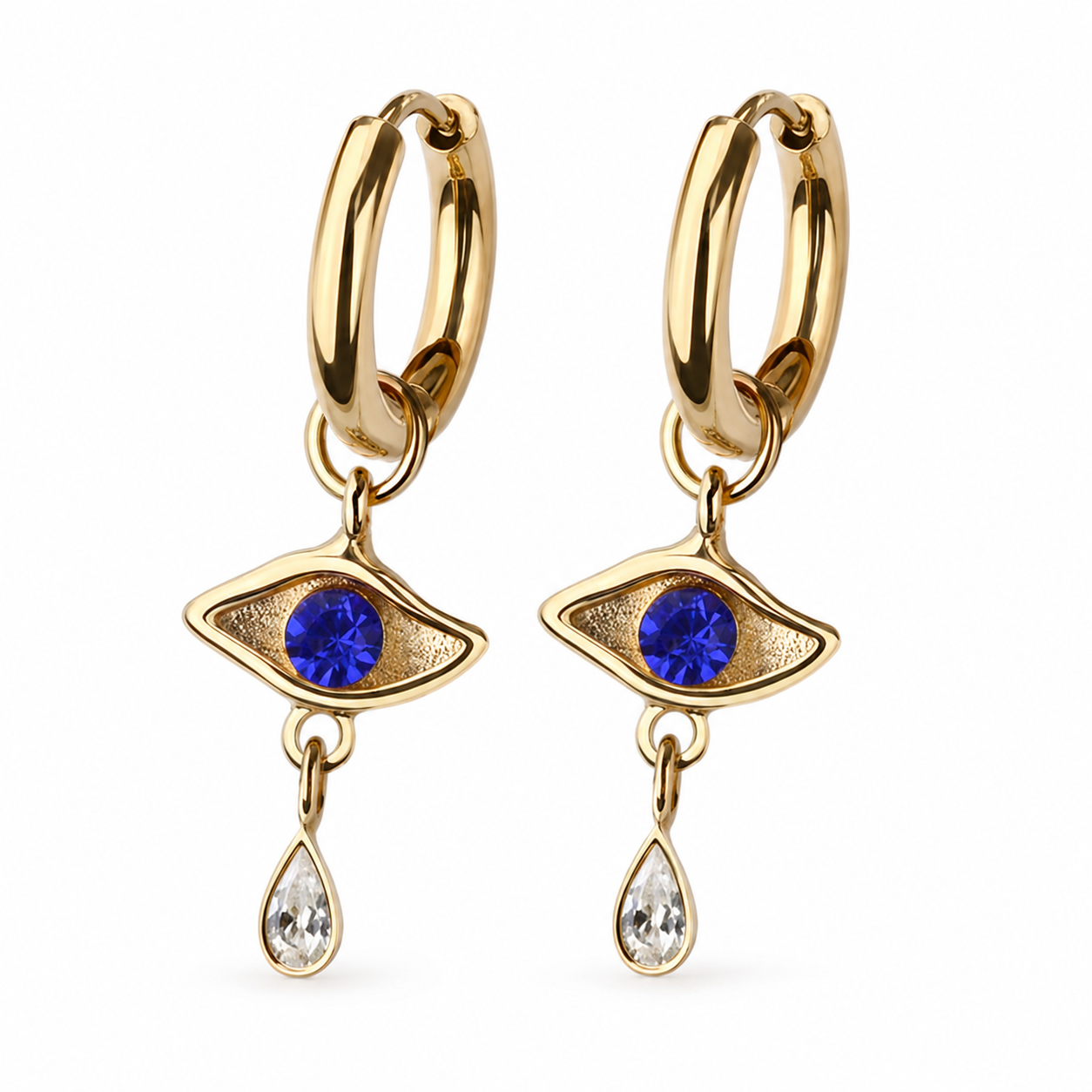 A pair of gold huggie hoop earrings with dangling eye charms. Each eye charm features a round blue gemstone in the center and a teardrop-shaped clear gemstone hanging below, set against a plain white background.