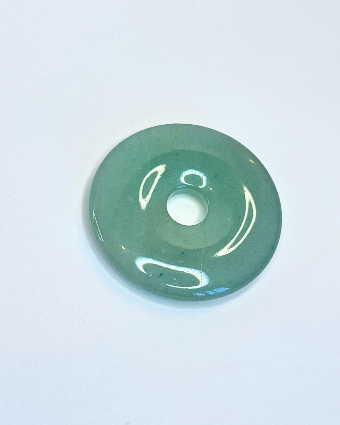 Green aventurine disc on a light blue background