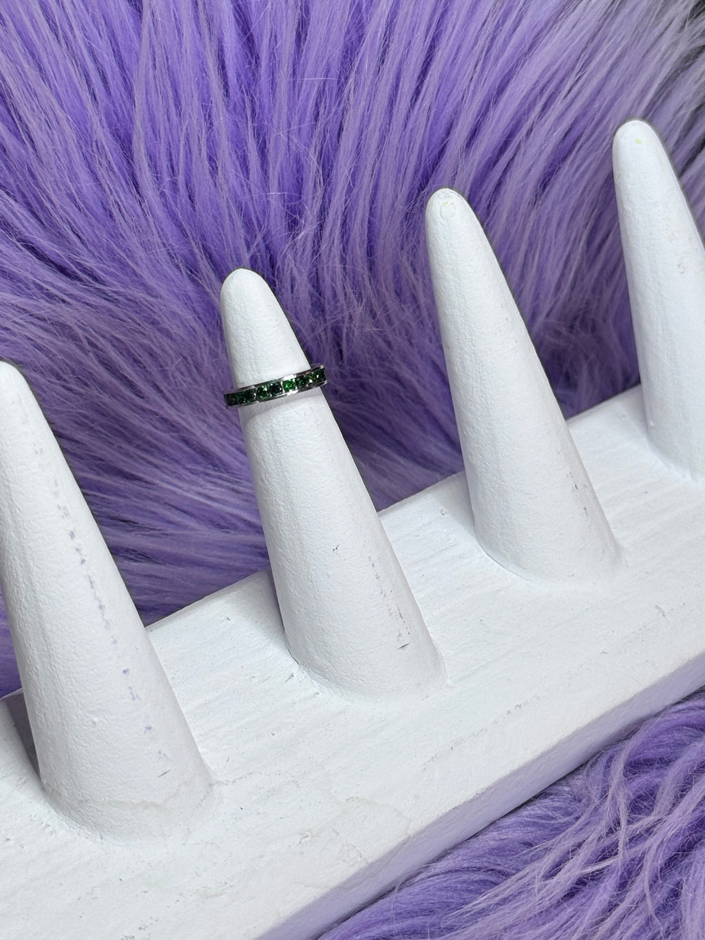 Ring on a white mannequin hand against a purple fur background