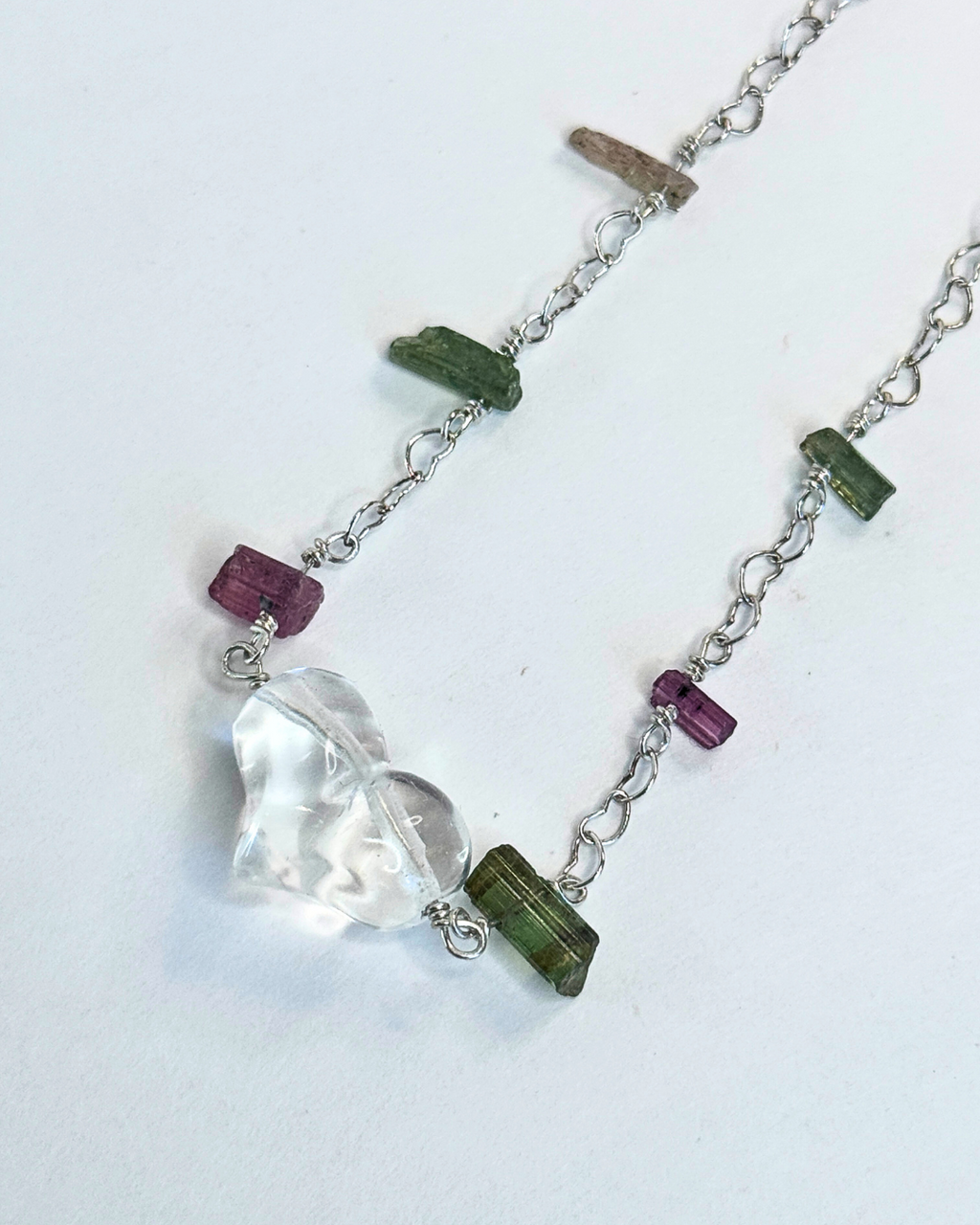 Necklace with a heart-shaped pendant and green and purple beads on a white background