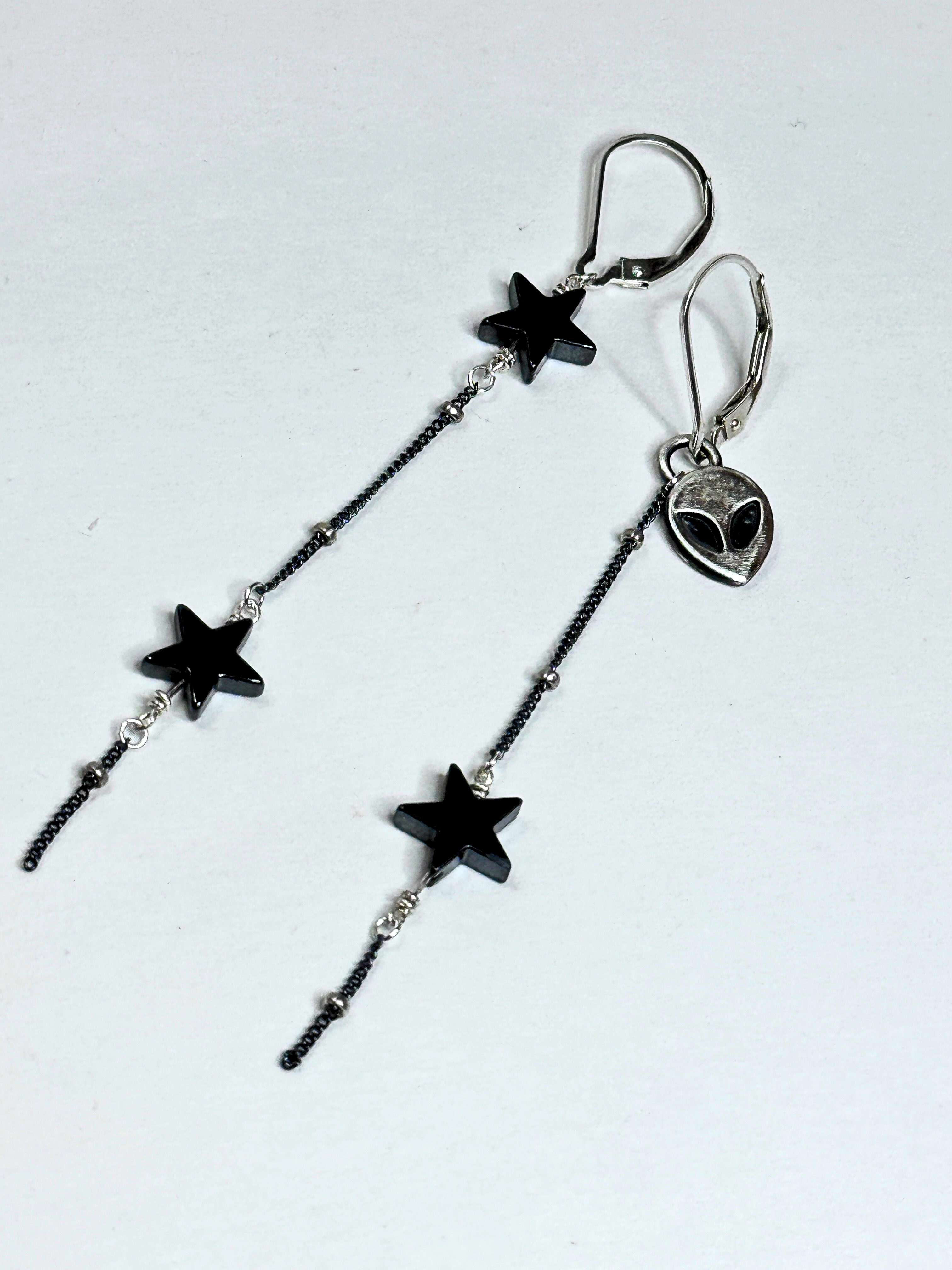Star-shaped earrings with a chain on a white background