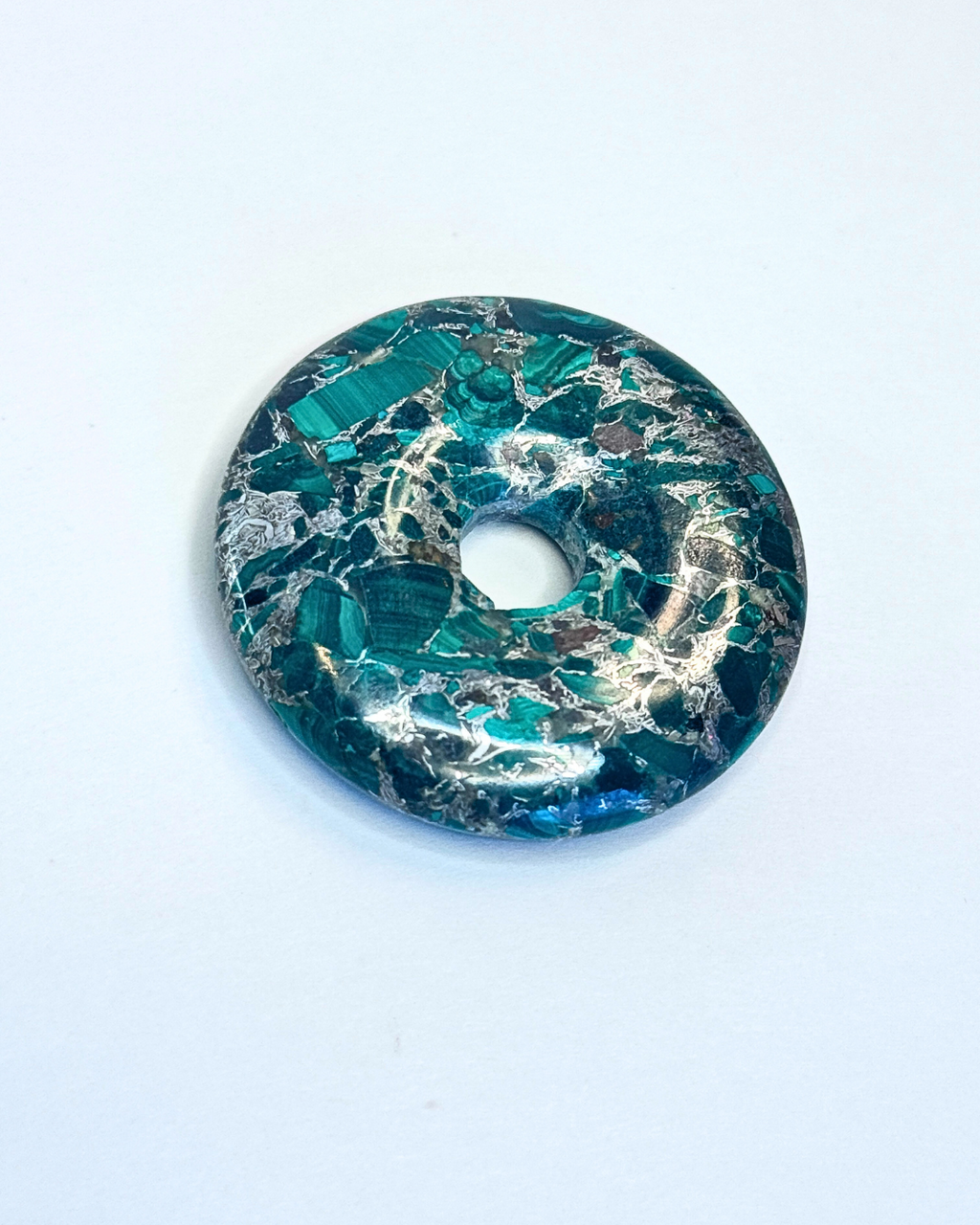 Decorative donut with green and gold marbled pattern on a white background
