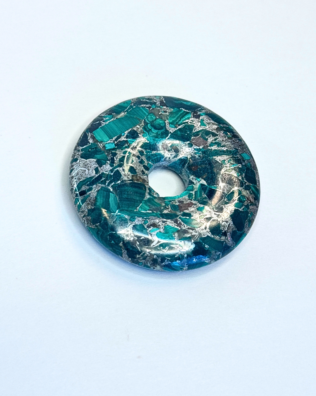 Decorative donut with green and gold marbled pattern on a white background