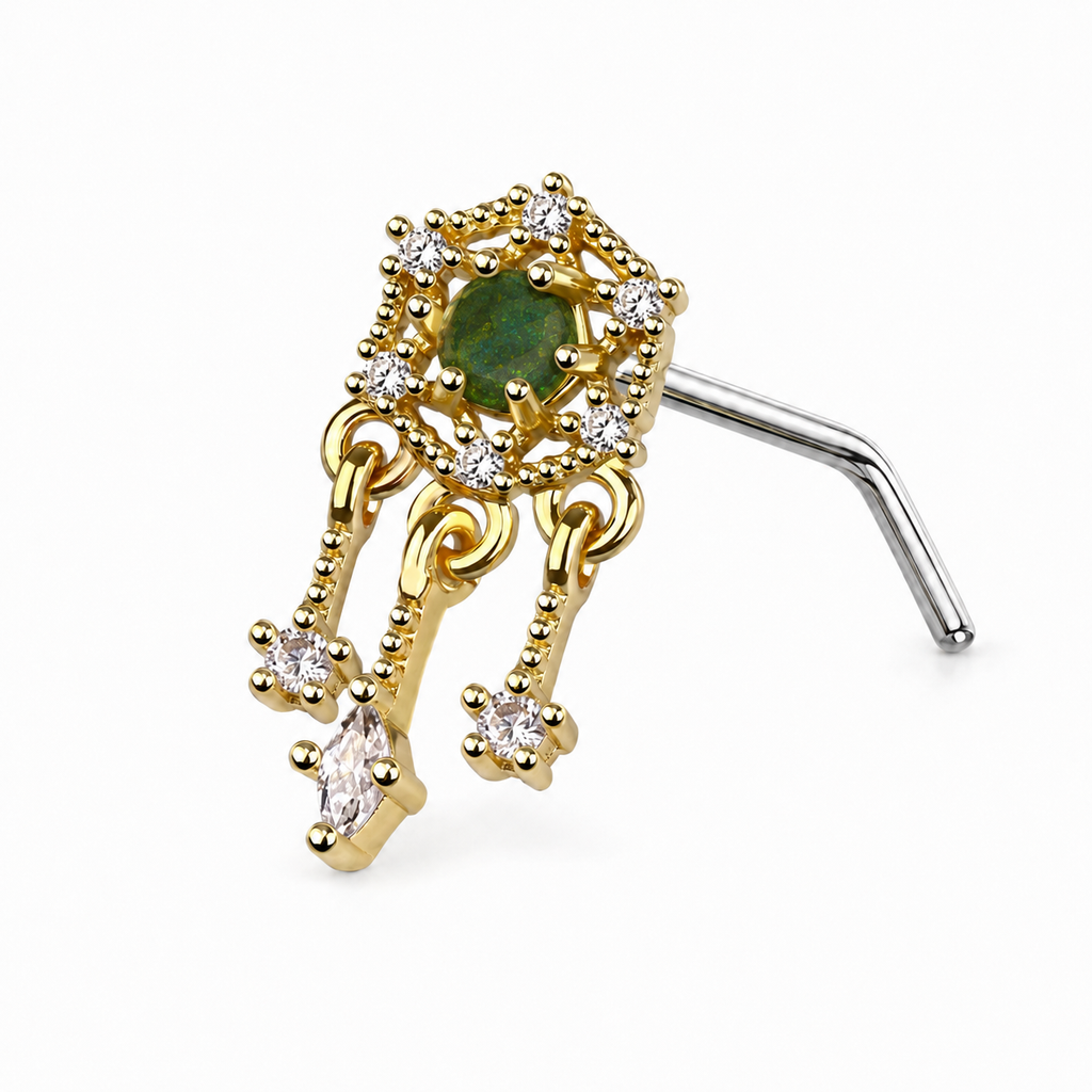 A gold and silver-toned labret piercing stud with a central green gemstone, surrounded by clear cubic zirconia accents, and featuring dangling chain-like elements with small clear stones on a white background.
