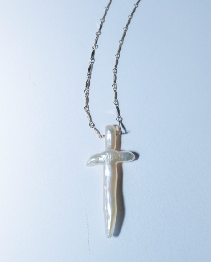 Silver dagger-shaped pendant on a chain against a light blue background