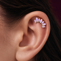 A close-up of a person's ear wearing a cluster of small marquise-shaped opal stud earrings in silver settings.