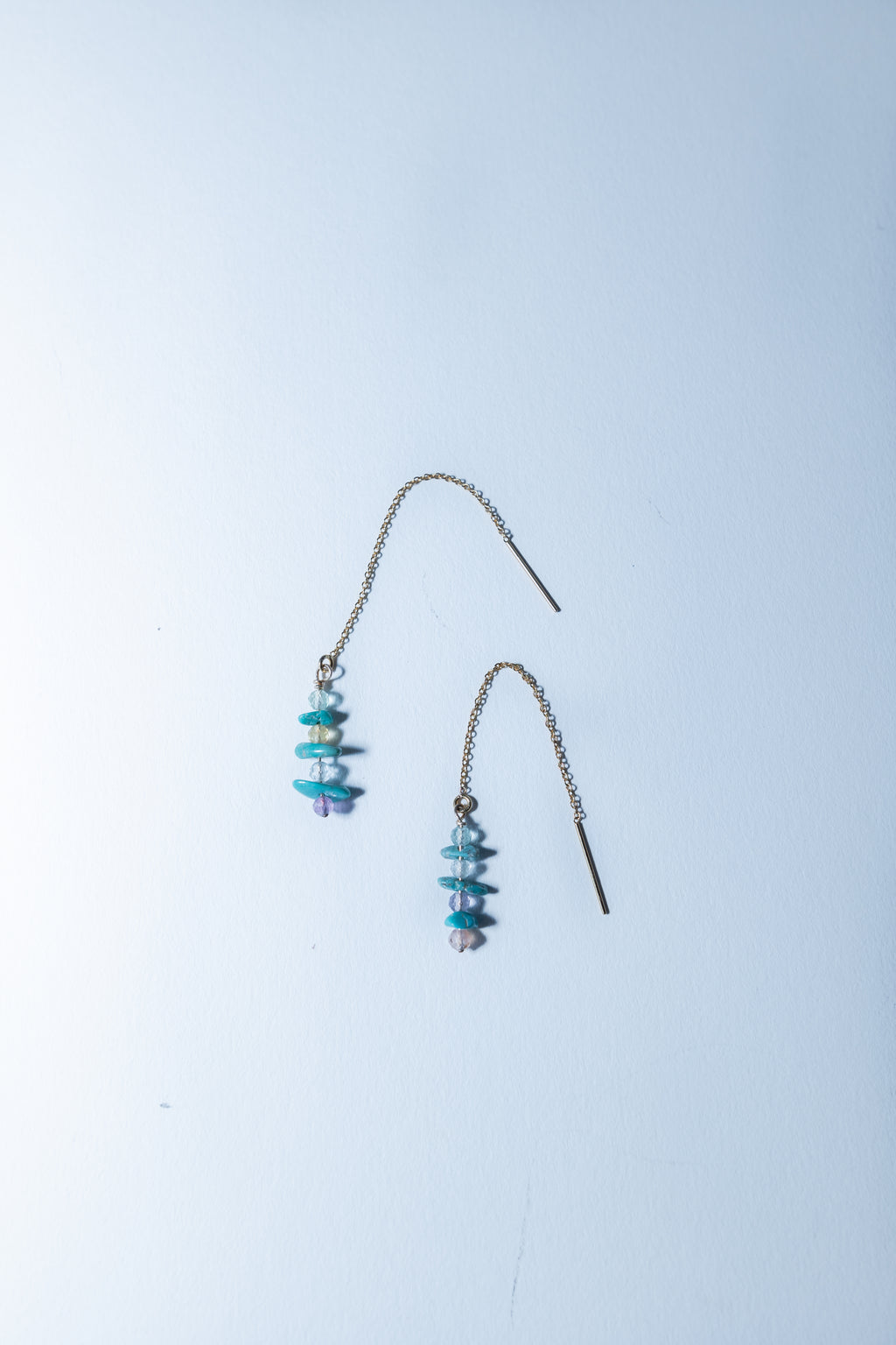 Pair of turquoise beaded earrings on a light blue background