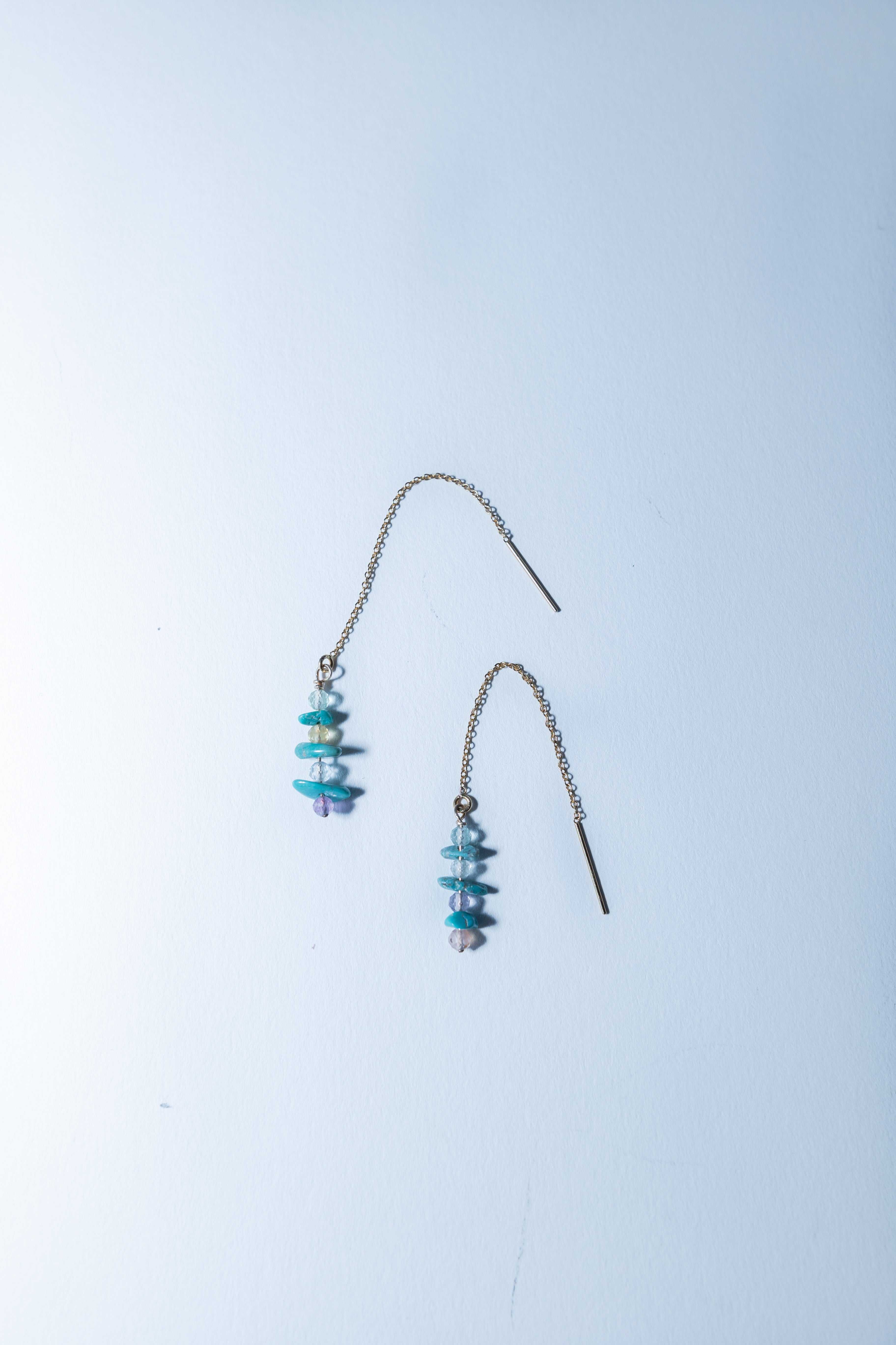 Pair of turquoise beaded earrings on a light blue background