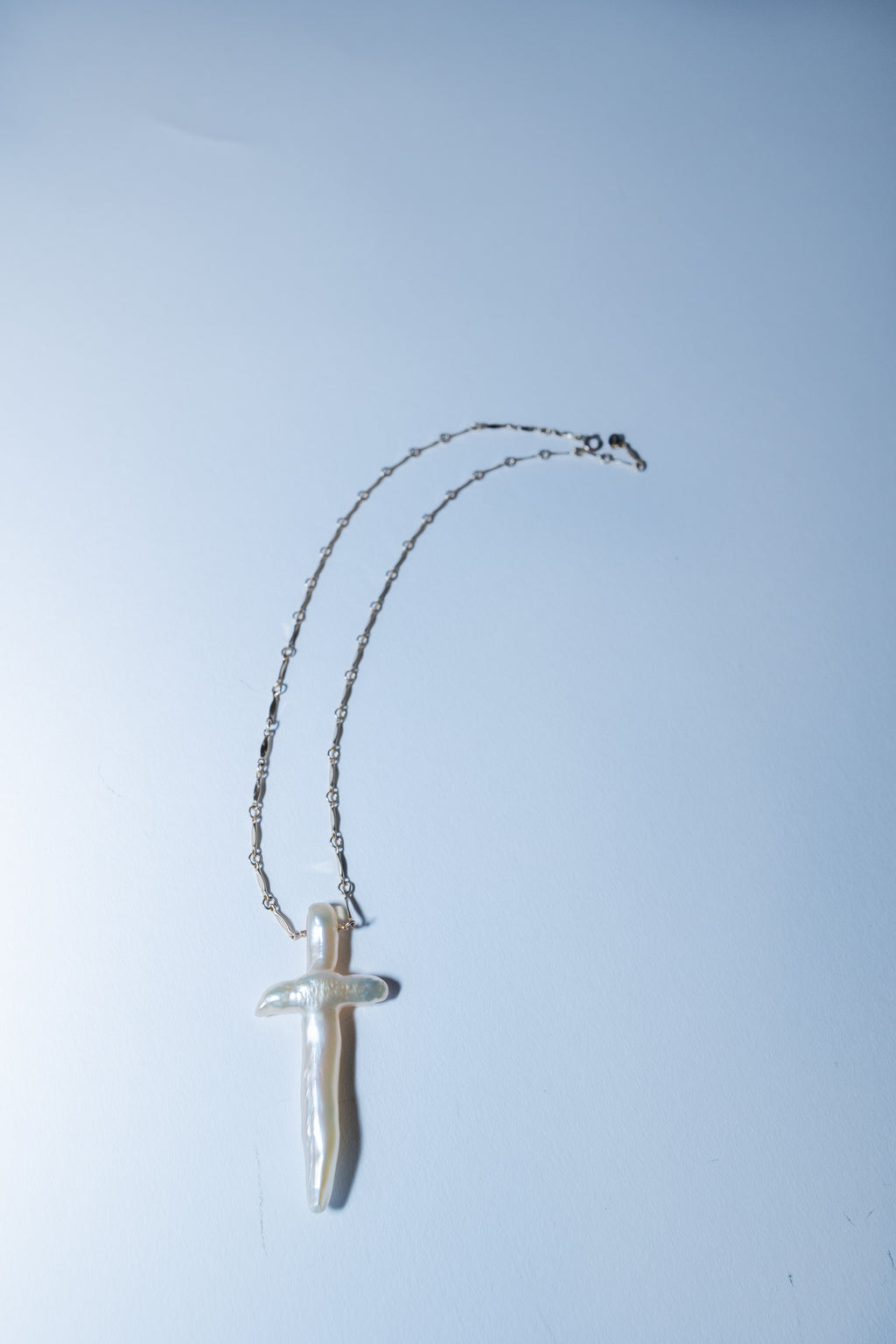 Silver necklace with a pendant on a light blue background