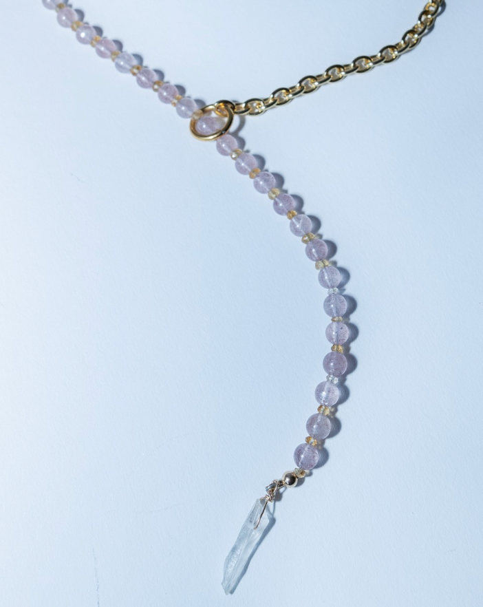 Necklace with pink beads and a crystal pendant on a light blue background