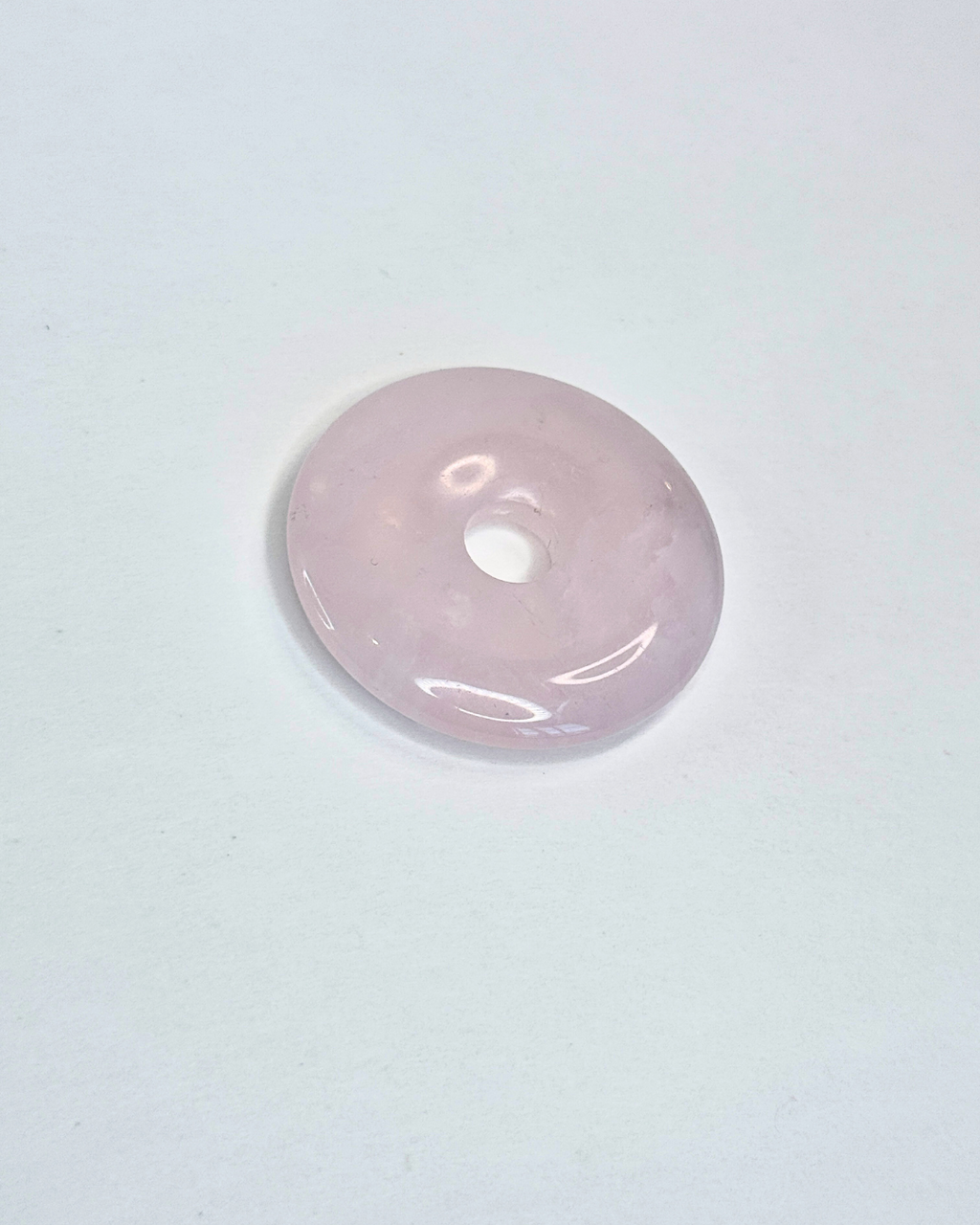 Pink donut-shaped object on a light gray background