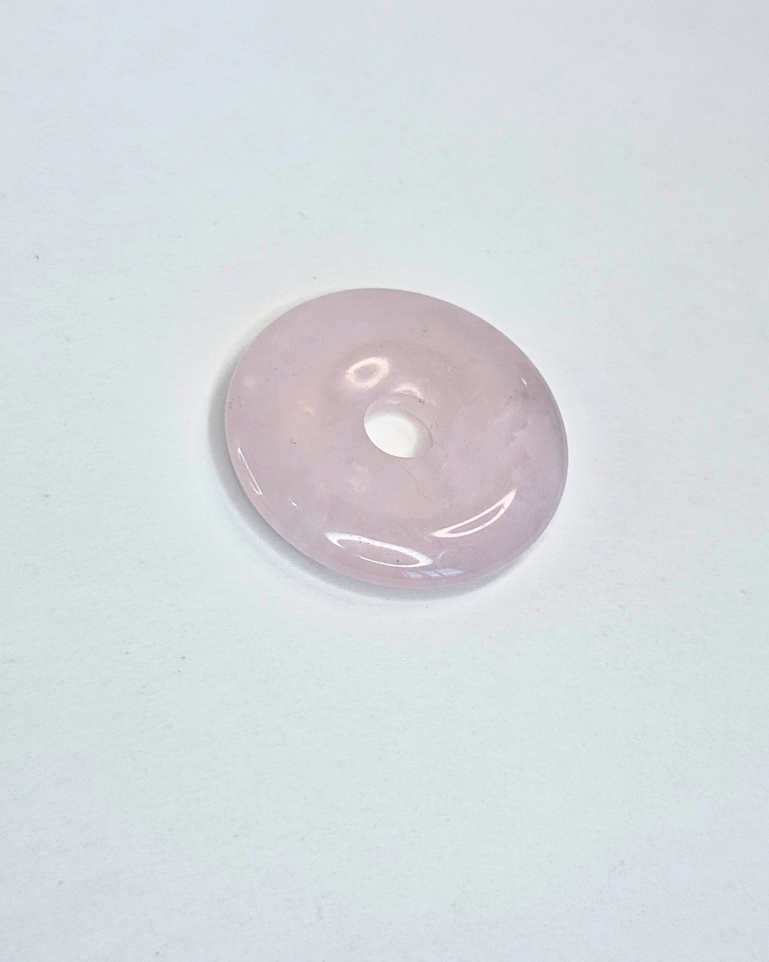 Pink donut-shaped object on a light gray background