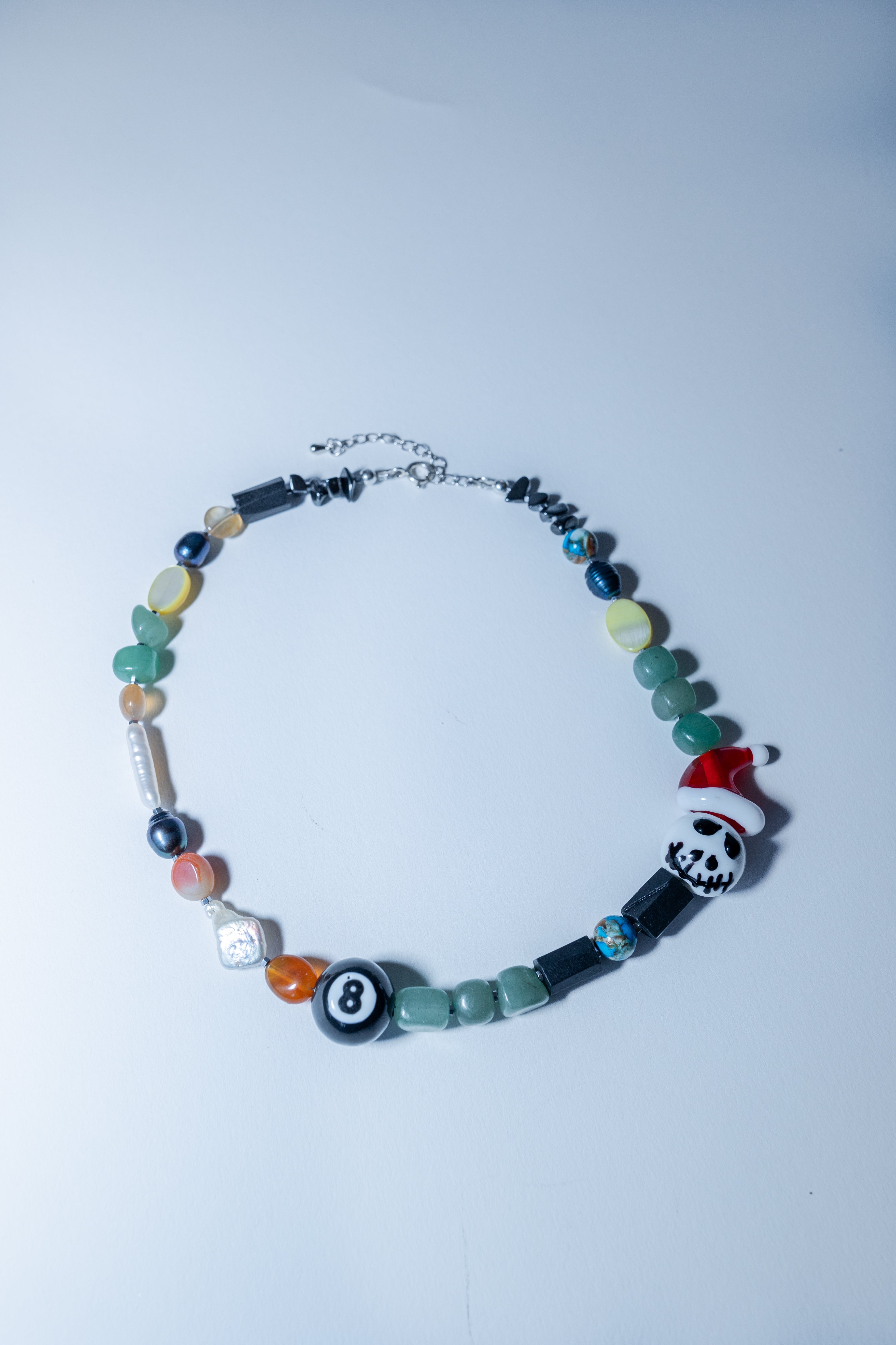 Colorful beaded bracelet with a skull and Santa hat charm on a light blue background