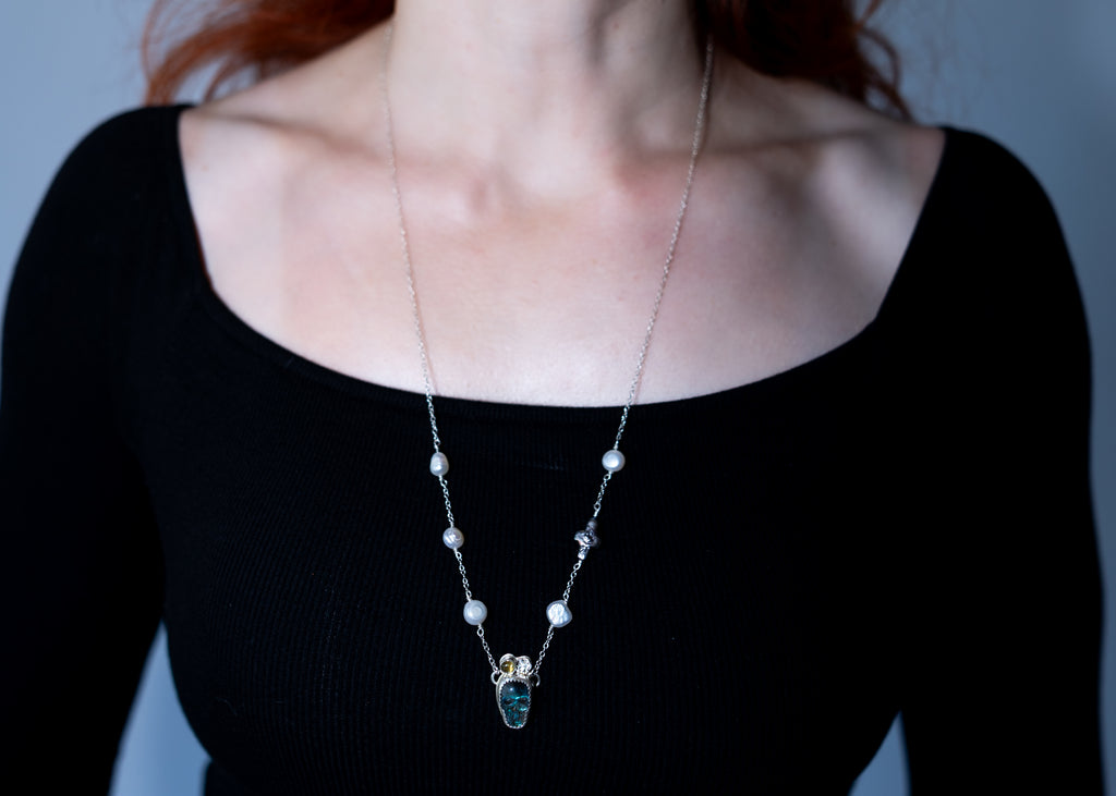 Necklace with a pendant worn by a person against a neutral background