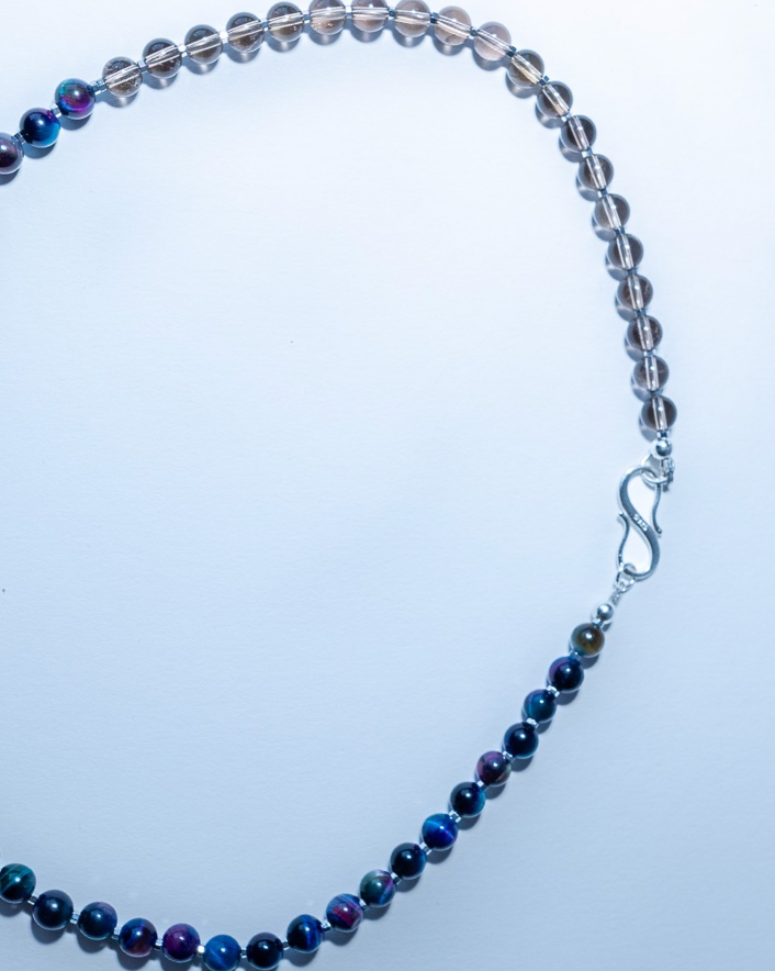 Necklace with blue beads and a silver clasp on a light blue background