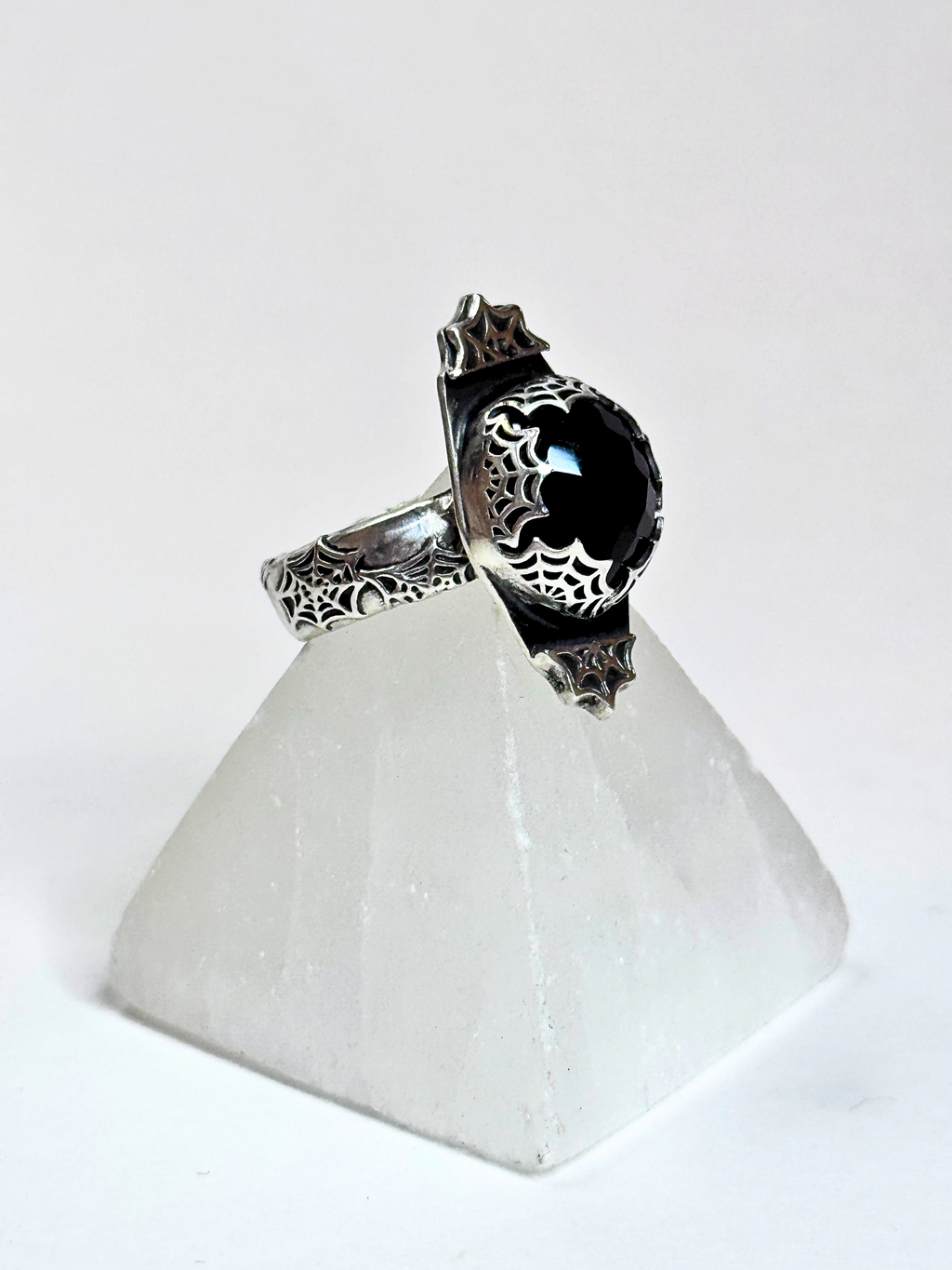 Silver ring with black stone on a white triangular stand
