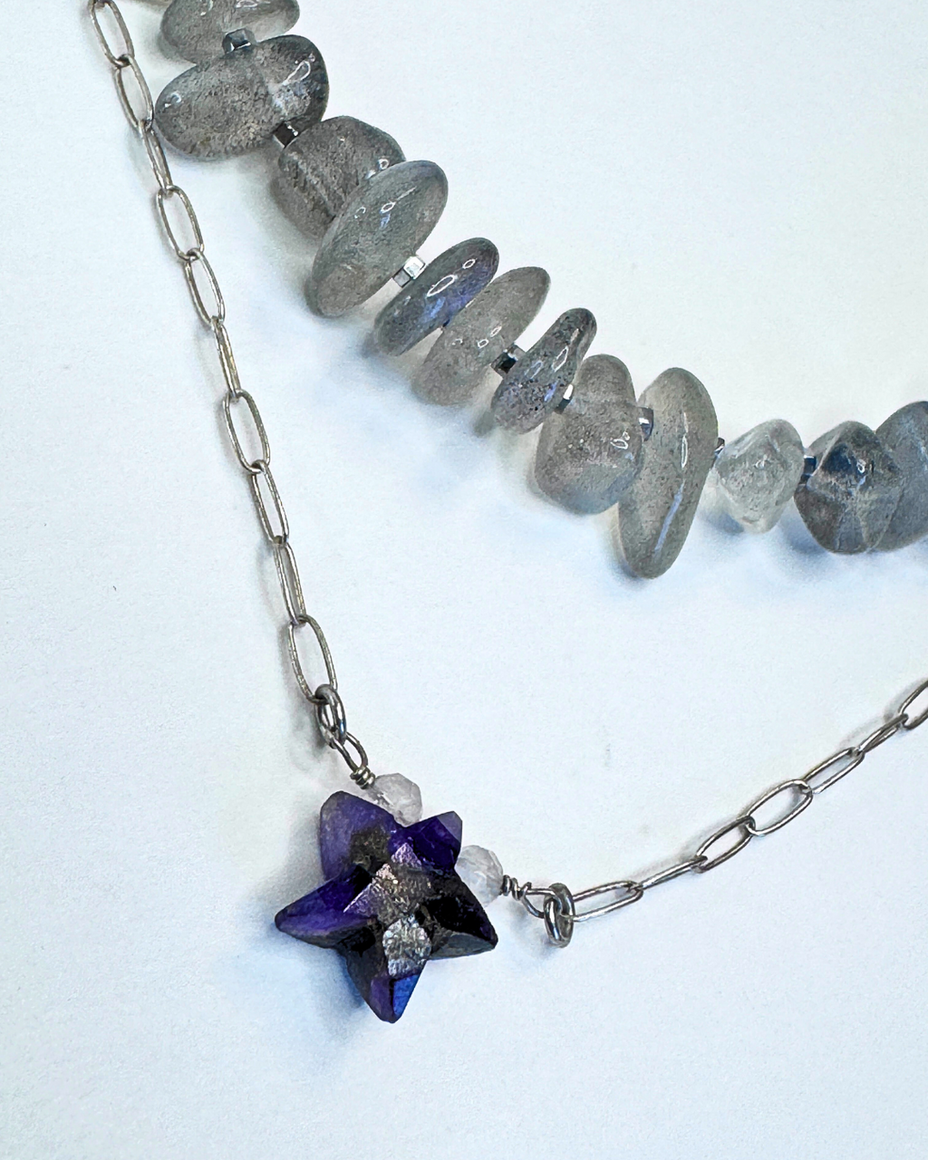 Necklace with purple star-shaped pendant and gray beads on a white background