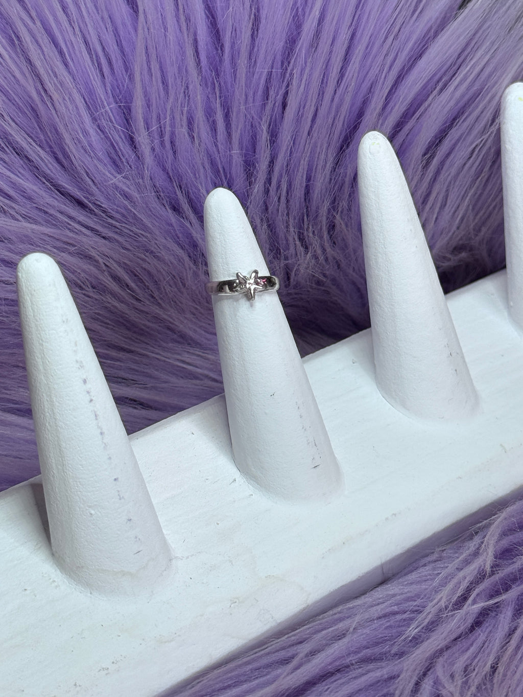 Silver ring on a white mannequin finger against a purple fur background