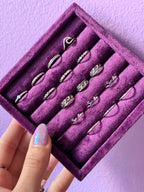 Purple jewelry box with silver toe rings on a light purple background