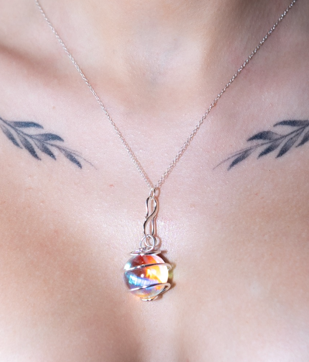 Necklace with a colorful pendant on a person's chest with tattoos