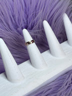 Gold ring on a white mannequin hand against a purple fur background